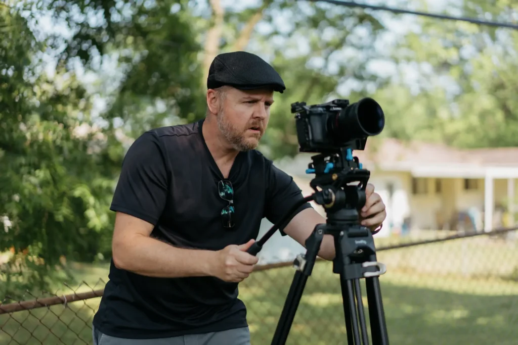 Professional videographer filming a corporate video production with a cinema camera on tripod for business marketing content.