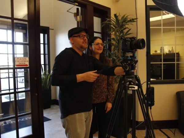 Professional testimonial video production team reviewing camera footage during a corporate video shoot for client storytelling.