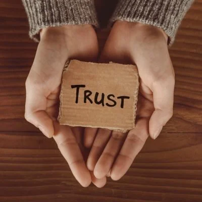 Hands gently holding a card reading "Trust," representing how a video production company builds credibility through storytelling.